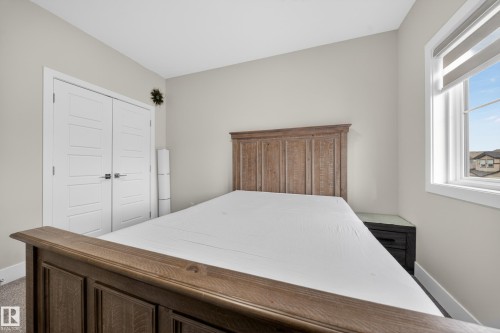 This room features a window providing natural light, light-colored walls, and a wood bed frame - 449 Roberts Crescent, Leduc, AB - Indoor Photo Showing Bedroom