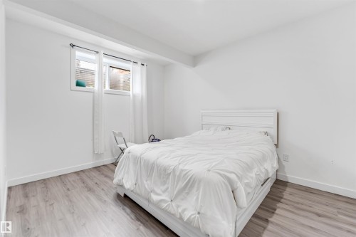 This room features light-toned wood flooring, clean white walls, and a window with white blinds and sheer white curtains - 449 Roberts Crescent, Leduc, AB - Indoor Photo Showing Bedroom