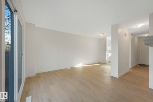 Empty room with light wood-style flooring and healthy amount of natural light - 5833 Riverbend Road, Edmonton, AB - Indoor Photo Showing Other Room