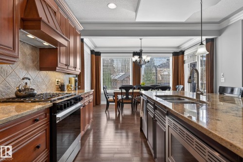 The property features a kitchen with rich wood cabinetry, granite countertops, and hardwood flooring - 20719 51 Avenue, Edmonton, AB - Indoor Photo Showing Kitchen With Double Sink With Upgraded Kitchen