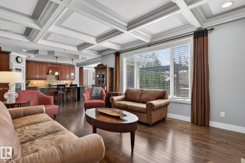 This inviting living space features rich hardwood flooring, a coffered ceiling, and a large window providing ample natural light - 20719 51 Avenue, Edmonton, AB - Indoor Photo Showing Living Room