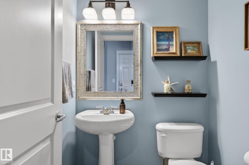 Bathroom featuring a pedestal sink, a framed mirror, and a toilet - 20719 51 Avenue, Edmonton, AB - Indoor Photo Showing Bathroom