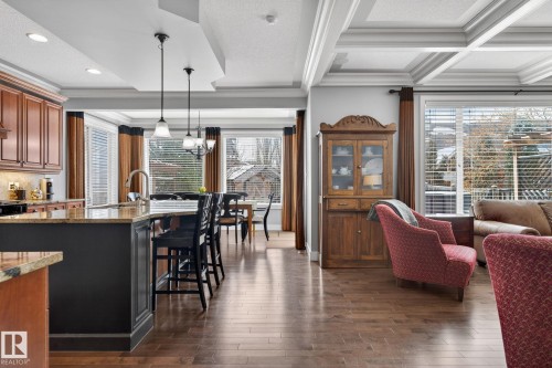This expansive interior features rich hardwood flooring, a coffered ceiling, and large windows that provide abundant natural light - 20719 51 Avenue, Edmonton, AB - Indoor Photo Showing Kitchen With Upgraded Kitchen