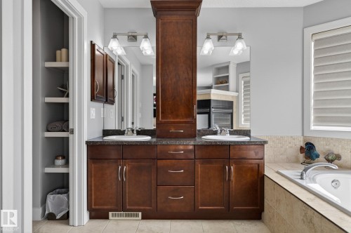 Bathroom featuring a dual vanity with dark wood cabinetry, granite countertops, and two undermount sinks - 20719 51 Avenue, Edmonton, AB - Indoor Photo Showing Bathroom