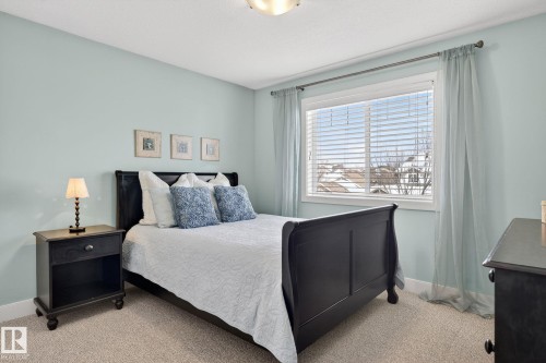 This room features light blue walls, a window with blinds and sheer curtains, and light-colored carpet flooring - 20719 51 Avenue, Edmonton, AB - Indoor Photo Showing Bedroom