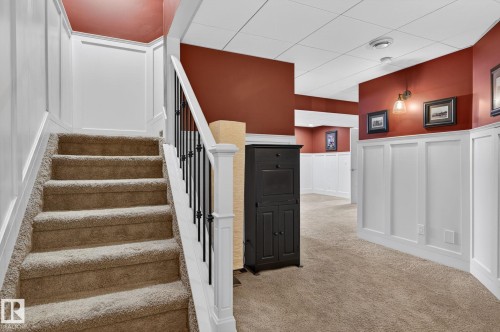 Carpeted staircase with white newel posts and black metal balusters - 20719 51 Avenue, Edmonton, AB - Indoor Photo Showing Other Room