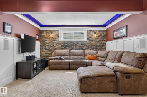 The living space features a stone accent wall, recessed lighting, and a window providing natural light - 20719 51 Avenue, Edmonton, AB - Indoor Photo Showing Living Room