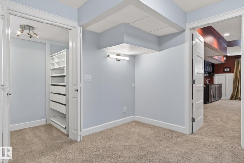This room features soft blue walls, light-colored carpeting, and a closet with custom shelving and drawers - 20719 51 Avenue, Edmonton, AB - Indoor Photo Showing Other Room