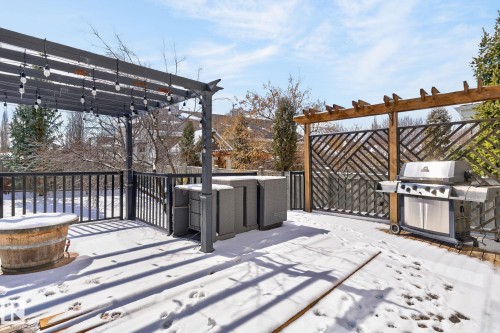 The property features an outdoor deck with a dark pergola adorned with string lights, a wood pergola with a decorative screen, and a visible barbeque grill - 20719 51 Avenue, Edmonton, AB - Outdoor With Exterior
