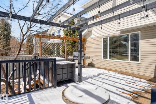 The property features a spacious deck with a black metal pergola, adorned with string lights - 20719 51 Avenue, Edmonton, AB - Outdoor