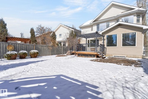The property features a spacious rear yard with a wooden privacy fence, a wooden deck with a pergola, and a stone patio - 20719 51 Avenue, Edmonton, AB - Outdoor