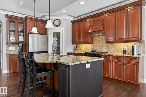 The kitchen features rich wood cabinetry, granite countertops, and stainless steel appliances - 20719 51 Avenue, Edmonton, AB - Indoor Photo Showing Kitchen With Upgraded Kitchen