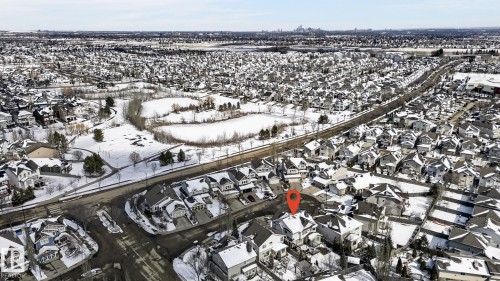 Aerial view of the property and its surrounding neighbourhood, featuring numerous houses with snow-covered roofs, and a distant city skyline under a clear sky - 20719 51 Avenue, Edmonton, AB - Outdoor With View