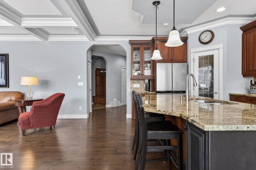 The property features rich hardwood flooring, a coffered ceiling, and a kitchen with a granite countertop island, pendant lighting, and stainless steel appliances - 20719 51 Avenue, Edmonton, AB - Indoor Photo Showing Kitchen With Upgraded Kitchen