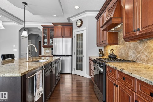 The kitchen features rich wood cabinetry, granite countertops, and hardwood floors - 20719 51 Avenue, Edmonton, AB - Indoor Photo Showing Kitchen With Stainless Steel Kitchen With Upgraded Kitchen