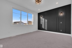 This room features a distinct accent wall with decorative paneling and sconce lighting, complemented by a large window providing natural light - 