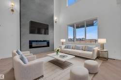 This living area features high ceilings, large windows providing ample natural light, and light-toned flooring - 