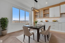Dining area featuring a modern light fixture, large windows, and herringbone wood flooring - 