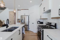 The kitchen features white cabinetry, stainless steel appliances, and light-colored countertops - 