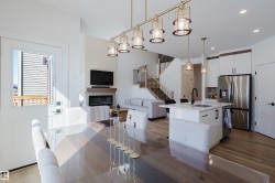The property features an open concept living area with light wood flooring, a modern fireplace, and a kitchen island with a sink and pendant lighting - 