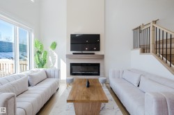 Bright living area featuring a fireplace, large windows providing natural light, and light-colored flooring - 