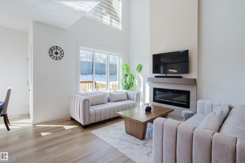 The living area features hardwood floors, a modern fireplace, and large sliding glass doors providing access to the outdoors - 79 Silverstone Drive, Stony Plain, AB - Indoor Photo Showing Living Room With Fireplace