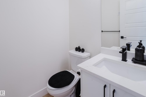 Bathroom featuring a white vanity with a white countertop and a rectangular sink, a black faucet, and a toilet with a black seat - 79 Silverstone Drive, Stony Plain, AB - Indoor Photo Showing Bathroom