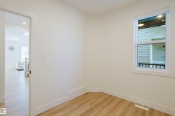 This room features light-colored walls, light wood flooring, and a window with white trim - 