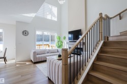 The property offers an open concept living area with high ceilings, large windows providing natural light, light wood-toned flooring, and a fireplace - 