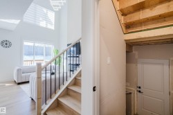 The property features a staircase with light wood steps and a black metal railing, leading to an upper level with visible wood framing - 