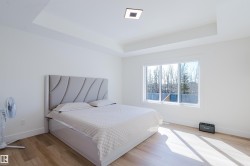 This bright room features a large window, a tray ceiling, and light-toned flooring - 