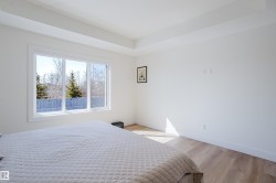 This bright room features a large window, light-toned flooring, and a tray ceiling - 