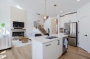 Open concept living area featuring a kitchen island with a double sink, a stainless steel refrigerator, and light wood flooring - 79 Silverstone Drive, Stony Plain, AB  - Indoor Photo Showing Kitchen With Fireplace With Double Sink With Upgraded Kitchen 