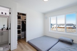 This room features white walls, hardwood flooring, and a window providing natural light and views of the surrounding area - 