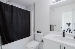 Bathroom featuring a white vanity with a rectangular sink, a black faucet, and a large mirror - 
