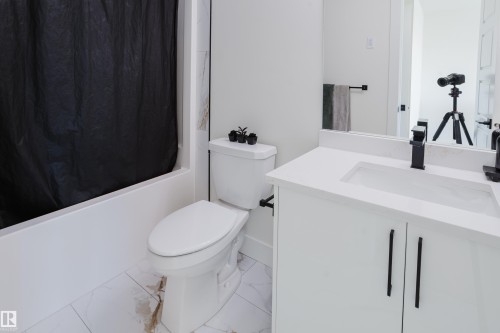 Bathroom featuring a white vanity with a rectangular sink, a toilet, a bathtub, and white tiled flooring - 79 Silverstone Drive, Stony Plain, AB - Indoor Photo Showing Bathroom