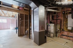 The unfinished basement features a concrete floor, exposed insulation, and a water heater - 