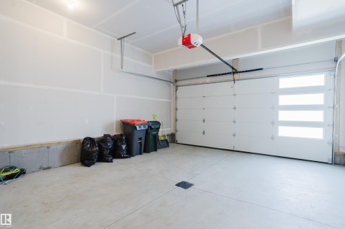 This garage features a concrete floor, a white overhead door with four rectangular windows, and an overhead door opener mechanism - 79 Silverstone Drive, Stony Plain, AB - Indoor Photo Showing Garage