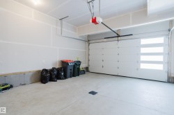 This garage features a concrete floor, a white overhead door with four rectangular windows, and an overhead door opener mechanism - 