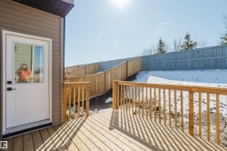 The property features a wooden deck with railing, a white exterior door with a window, and brown siding - 