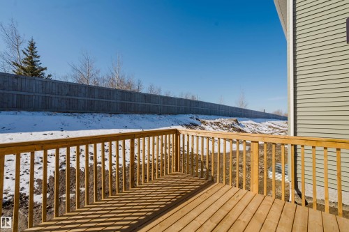 The property features a wooden deck with a railing overlooking a sloped yard - 79 Silverstone Drive, Stony Plain, AB - Outdoor