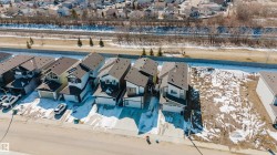 The property is situated in a neighbourhood with other properties of a similar style and features a paved driveway and an attached garage - 