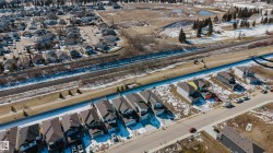 Aerial view showcasing the residential street with a variety of homes, paved roads, and a clear view of the surrounding neighbourhood - 