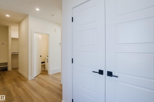 The property features modern white panel doors with matte black hardware, light-toned wood flooring, and recessed lighting - 79 Silverstone Drive, Stony Plain, AB - Indoor Photo Showing Other Room