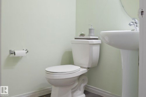 The bathroom features a white pedestal sink with a chrome faucet, and a white toilet - 4783 Crabapplle Run, Edmonton, AB - Indoor Photo Showing Bathroom