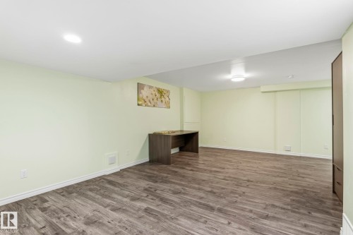 Spacious room featuring light green walls, recessed lighting, and wood-style flooring - 4783 Crabapplle Run, Edmonton, AB - Indoor