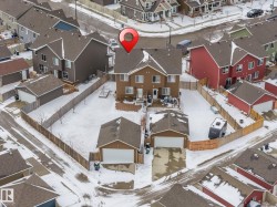 Aerial view of the property, showcasing the main residence, two detached garages, and a fenced yard - 