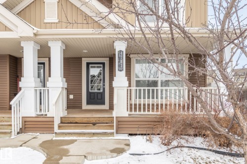 This property features a front porch with white columns and railings, a brown exterior with white trim, and a prominent front door with glass panels - 4783 Crabapplle Run, Edmonton, AB - Outdoor