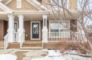 This property features a front porch with white columns and railings, a brown exterior with white trim, and a prominent front door with glass panels - 4783 Crabapplle Run, Edmonton, AB  - Outdoor 