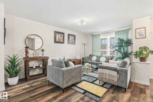 Living space with dark wood-style flooring, light-colored walls, and large windows with light blue curtains - 4783 Crabapplle Run, Edmonton, AB - Indoor Photo Showing Living Room